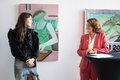 Julia Tymanska und Antje Grotheer stehen vor mehreren Gemälden.